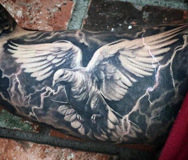 Black and grey tattoo of a detailed dove with outstretched wings, surrounded by lightning bolts for a dramatic effect on the bicep