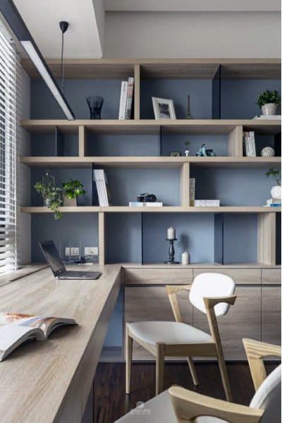 Modern home office with wooden desk, shelves, books, plants, a laptop, and a white chair