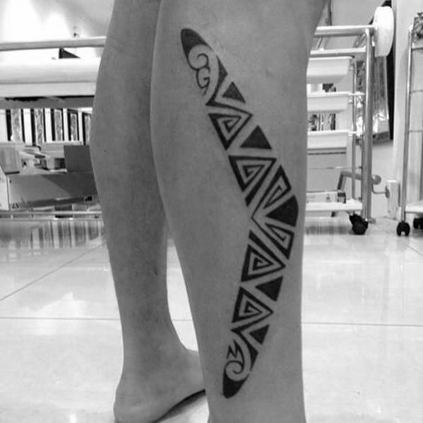Large boomerang tattoo on the calf featuring bold tribal-style geometric patterns in black ink.