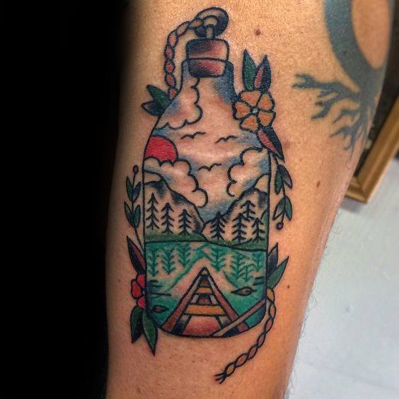 Alt text: Tattoo of a canoe inside a bottle, surrounded by trees, flowers, and a cloudy sky, capturing a serene natural scene in vibrant colors.
