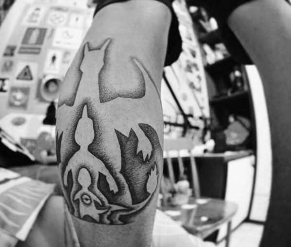 Black and gray tattoo featuring silhouettes of Charizard, Mewtwo, and Mew in a layered design with smooth shading and bold contrast.