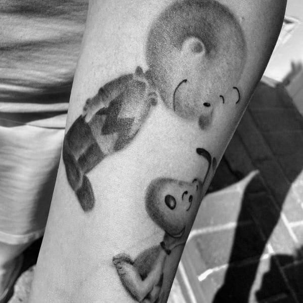 Black and white Charlie Brown and Snoopy tattoo, featuring a playful floating effect, symbolizing joy, nostalgia, and friendship.