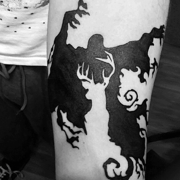 Bold blackwork tattoo of a Dementor and a glowing stag Patronus, with swirling magical elements on the forearm.