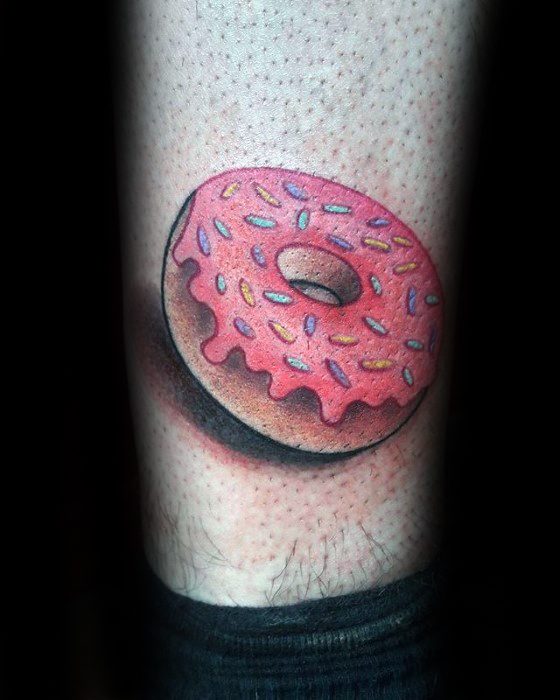 Tattoo of a realistic pink frosted donut with colorful sprinkles and a bold shadow for a 3D effect on the lower leg.
