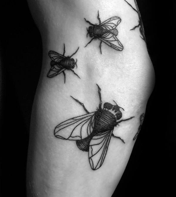 Black ink tattoo of multiple flies in varying sizes, arranged organically across the arm for a realistic crawling effect.