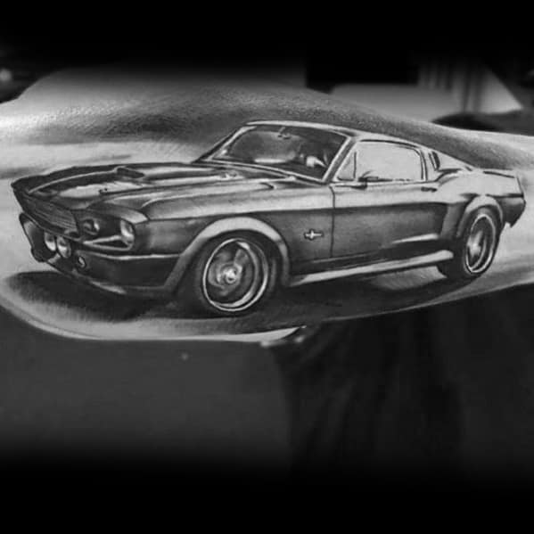 Realistic black and grey Ford Mustang tattoo on forearm, showcasing detailed shading, sleek body lines, and a powerful muscle car design.