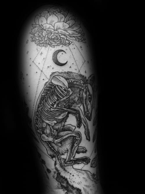 Intricate tattoo of a fox with exposed skeleton, surrounded by stars, a crescent moon, and a blooming flower above.