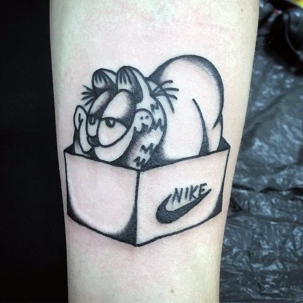 Black and gray Garfield tattoo of him playfully sitting in a Nike shoebox, blending humor with a love for sneakers.