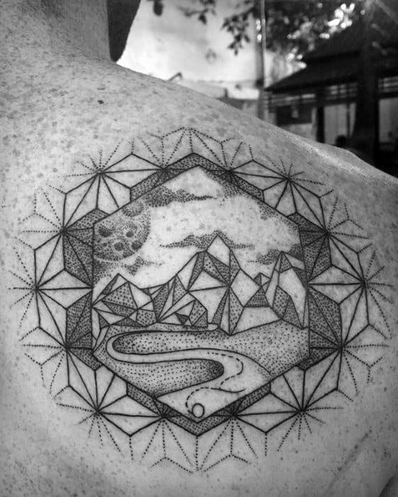 Detailed geometric tattoo on the shoulder with mountains, moonlit sky, river, and hexagonal mandala-style border.