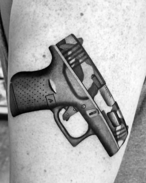Realistic black and grey tattoo of a Glock pistol on the skin, featuring detailed shading and depth, giving it a three-dimensional appearance.