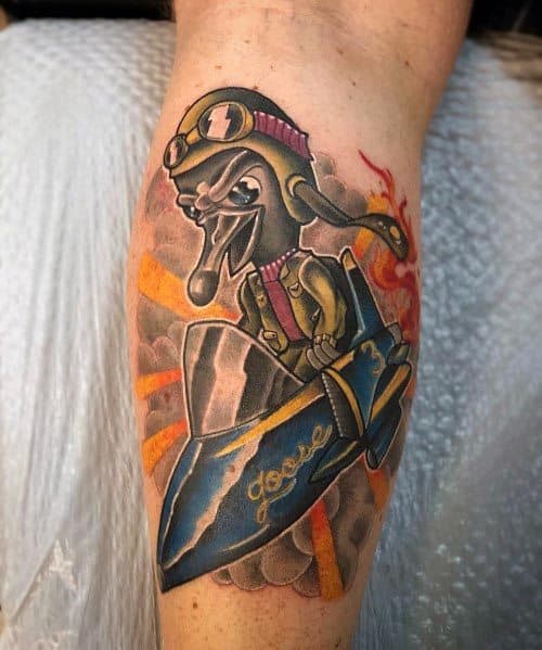 Colorful tattoo of a cartoon-style goose wearing pilot goggles and a scarf, riding a rocket labeled "Goose," with flames and smoke in the background.