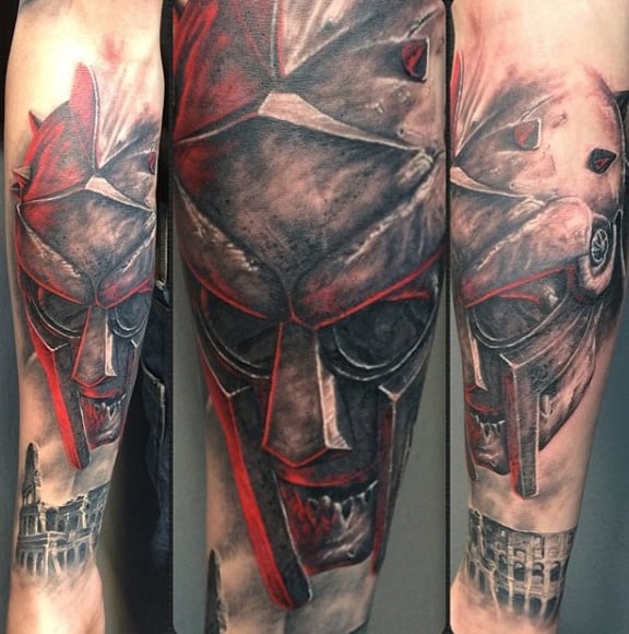 Masked gladiator with red accents and detailed architectural elements tattoo on forearm