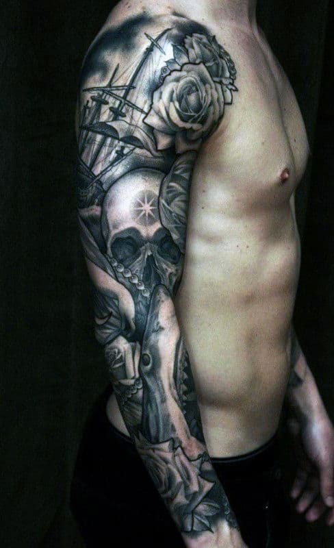 Man with a full sleeve tattoo featuring a skull, rose, and various intricate designs