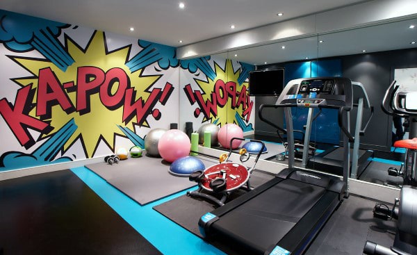 Home gym with colorful comic-style wall art, treadmill, exercise balls, and yoga mats for a vibrant home workout