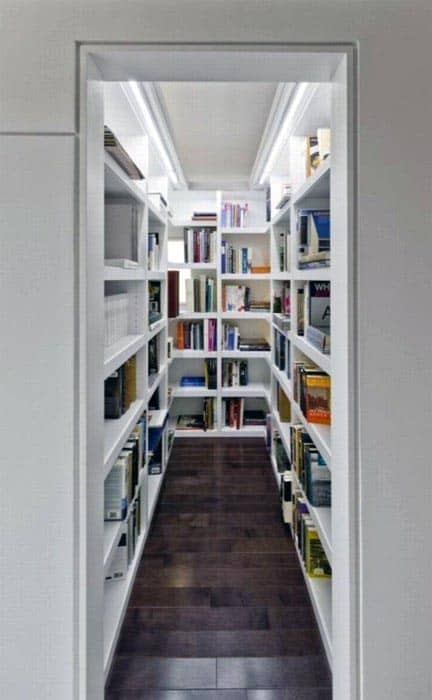A narrow library hallway filled with white bookshelves, lined with various books on both sides