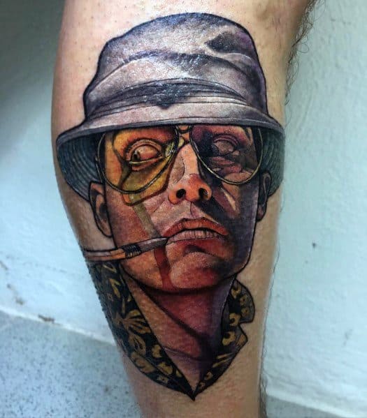 Realistic Hunter S. Thompson tattoo featuring his iconic bucket hat, aviator glasses, and cigarette, with bold shading and vibrant colors.