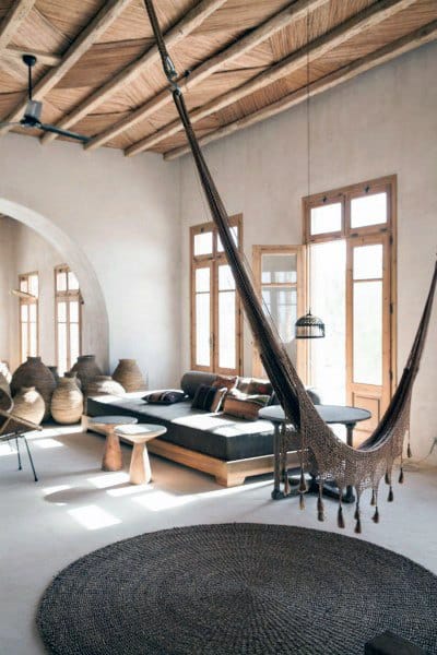 Brown indoor hammock in a rustic living room with natural light and earthy decor elements.