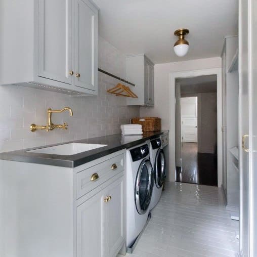 Gray laundry room with gold accents, modern appliances, and built-in hanging space.