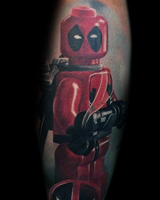Realistic tattoo of a Lego Deadpool minifigure in vibrant red, holding weapons and featuring detailed shading and comic-style expression.