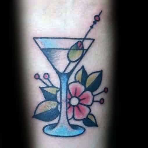 Traditional-style martini glass tattoo with an olive garnish and floral accents. A bold, classic design with vibrant colors and clean lines.