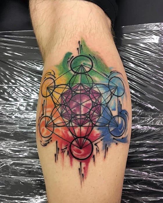 Metatron’s Cube thigh tattoo with bold black lines over a vibrant watercolor splash of red, green, yellow, blue, and purple hues.