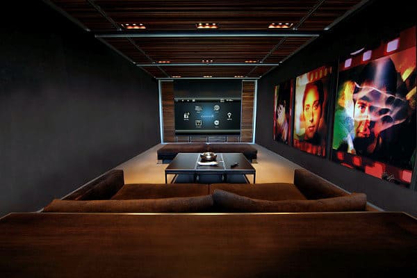 Modern home theater with dark sofas, large screen, and vibrant movie posters adorning the walls