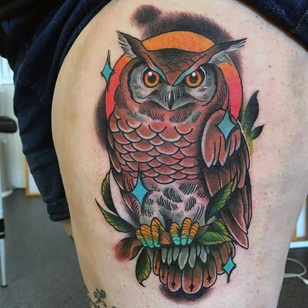 Neo-traditional owl tattoo with bold outlines, rich shading, and vibrant details, featuring a sunset backdrop and decorative elements.