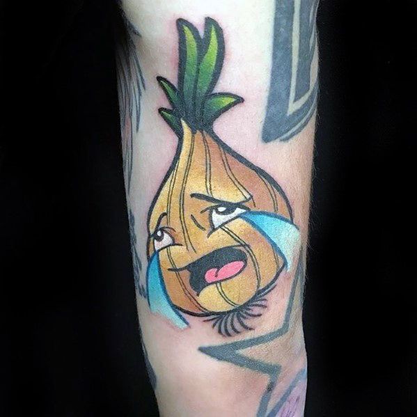 Colorful cartoon-style onion tattoo on the forearm, featuring a crying anthropomorphic onion with green sprouts and exaggerated facial expressions.