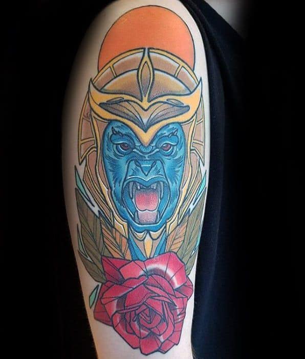 Striking tattoo of Rita Repulsa’s blue monkey warrior Goldar, detailed with bold colors, a red rose, and an orange sun backdrop.