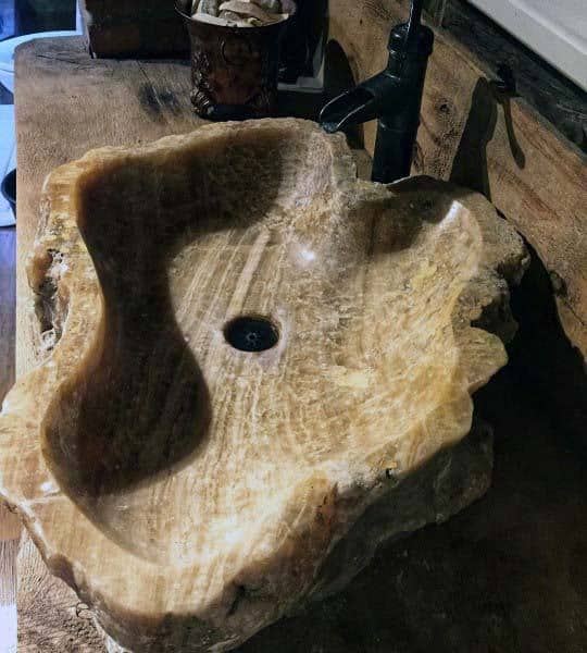 Rustic stone sink with an organic shape on a weathered wooden countertop