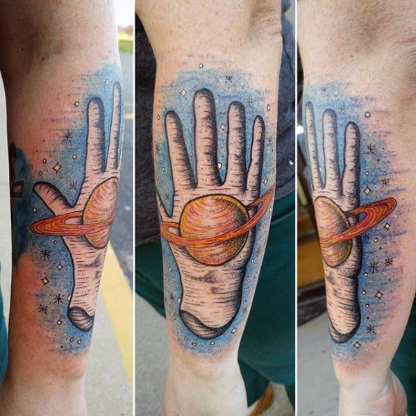 Whimsical Saturn tattoo design for men featuring a surreal hand with the planet's rings and a colorful cosmic background.