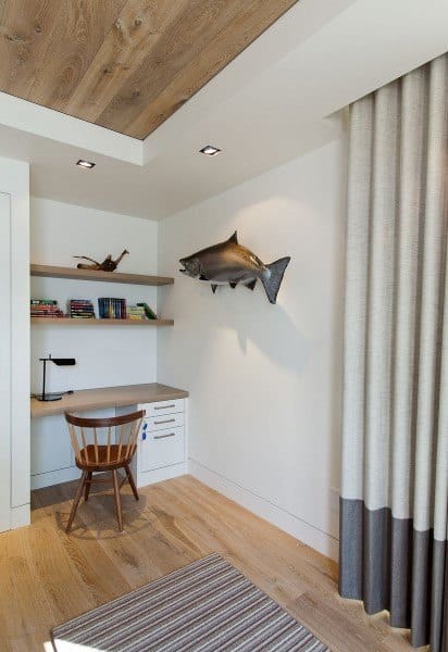 Minimalist study nook with built-in wooden desk, chair, shelves, books, and a mounted fish in neutral tones