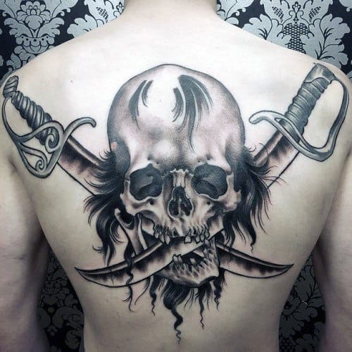 Pirate-style skull back tattoo with crossed swords and fierce expression, surrounded by wild hair and dramatic shading.