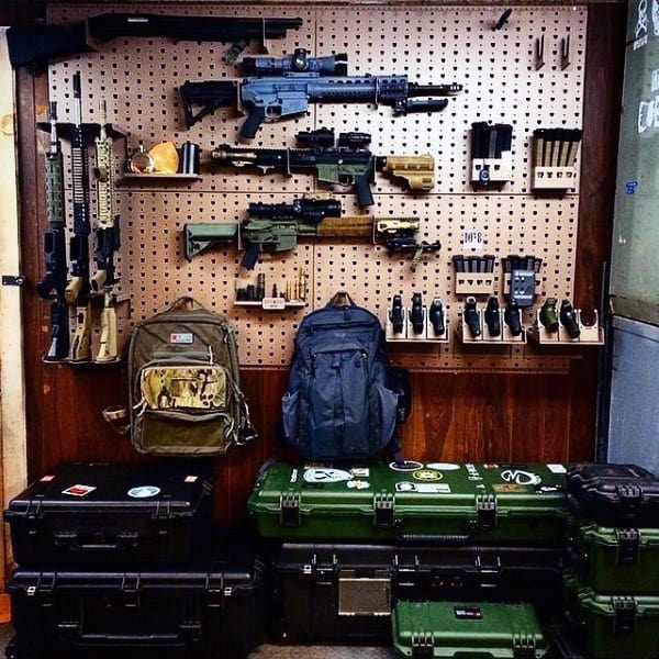 Gun room with pegboard displaying rifles, gear, and ammo cases stacked below.