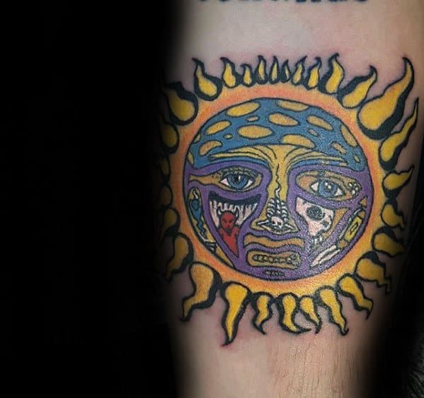 Classic Sublime sun face tattoo with bold yellow flames, blue and purple tones, and expressive facial details.