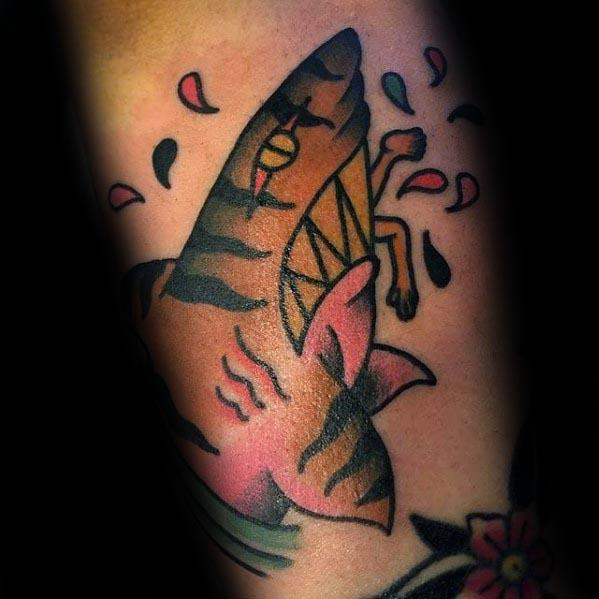 Playful tiger shark tattoo with bold lines, sharp teeth, yellow eye, and pink accents, splashing through drops and floral elements.