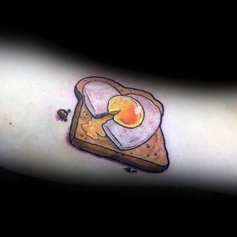 Realistic toast tattoo with a heart-shaped egg in the center, featuring warm tones and subtle shading for a soft, artistic food-inspired design.