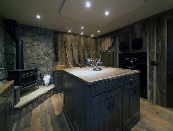 Rustic gun room with a wooden interior, a central storage island, and a cozy fireplace.