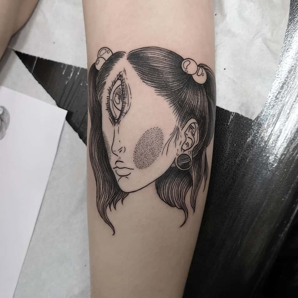 Tattoo of a surreal female face with a third eye, fine line details, and textured shading, inked on the forearm.