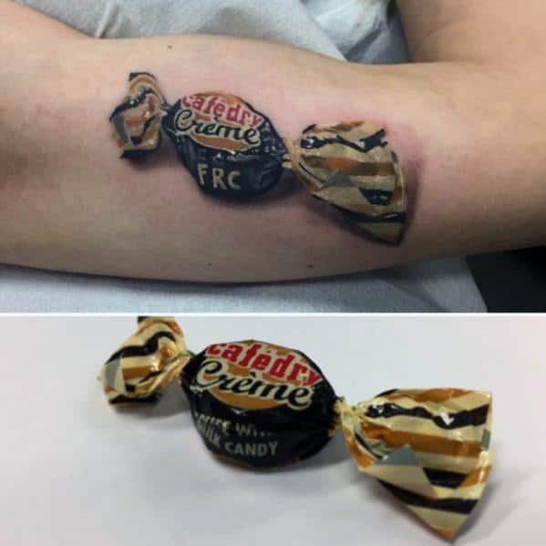 Hyperrealistic tattoo of a Café Crème candy with intricate shading and highlights, replicating the wrapper’s texture and reflective details.