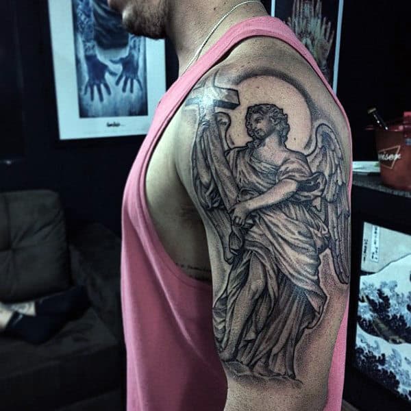 A person with an angel and cross tattoo on their upper arm
