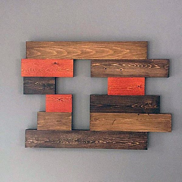 Wooden wall art with staggered brown and orange planks forming a geometric pattern on a gray background