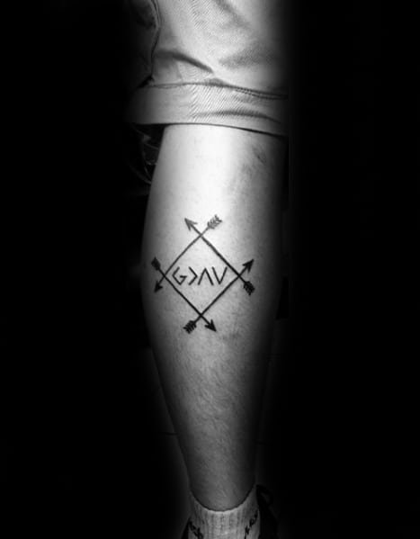 Leg tattoo featuring "God is greater than the highs and lows" symbol surrounded by crossed arrows in geometric design