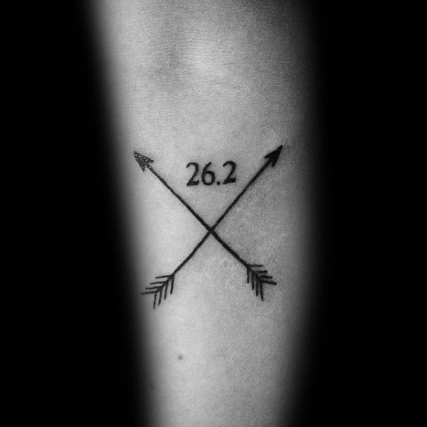 Minimalist crossed arrows tattoo with 26.2 at the center, symbolizing direction, strength, and the journey of a marathon runner.