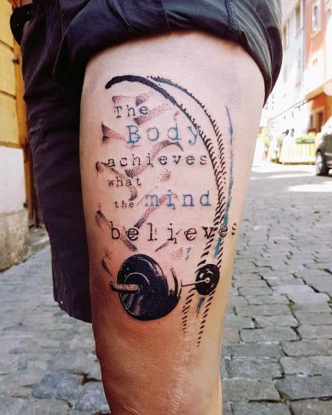 Inspirational fitness tattoo featuring a barbell, feather, and the quote "The body achieves what the mind believes," symbolizing strength and determination.