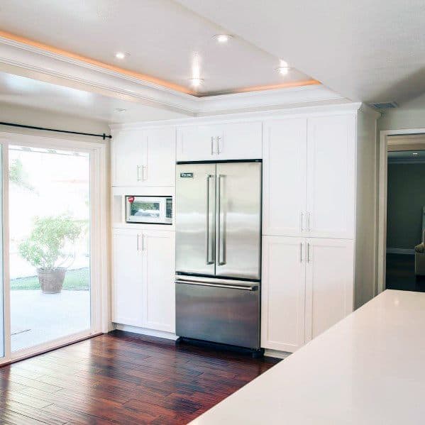 Modern kitchen with crown molding lighting, sleek white cabinetry, and stainless steel appliances