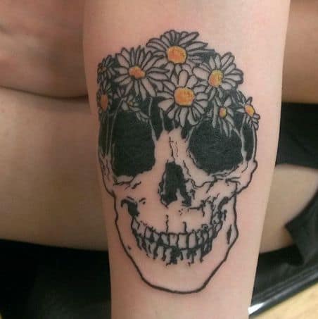 Forearm tattoo black and grey skull with crown of white and yellow daisies