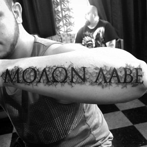 Crushed Stone Black Ink Molon Labe Design Tattoo On Mans Outer Forearm