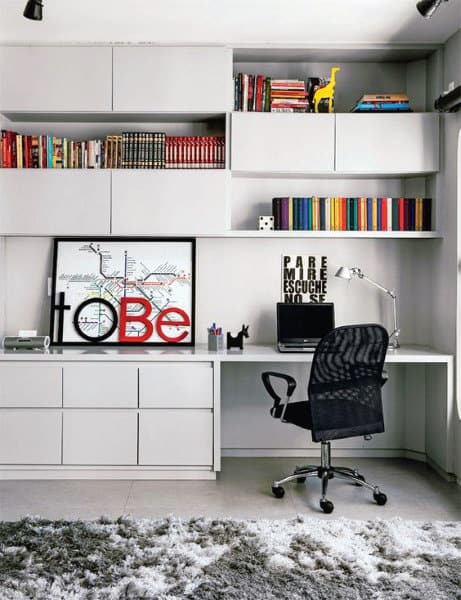 Modern home office with a desk, computer, bookshelf, colorful books, and a gray chair on a shag rug