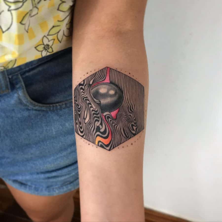 Forearm tattoo featuring a hexagonal design with fluid woodgrain patterns, a black sphere, and vibrant orange-pink accents for a surreal effect.